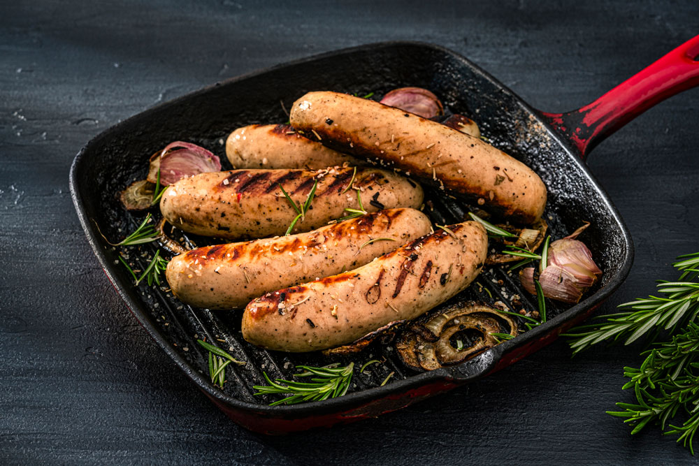 Bilde av ulike pølser som er stekt i en panne